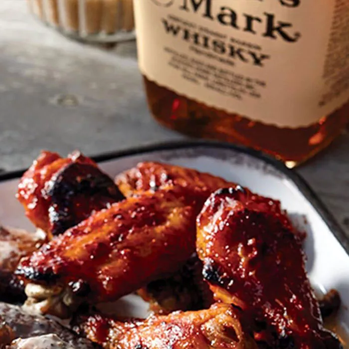 plate of chicken wings next to bottle of makers mark