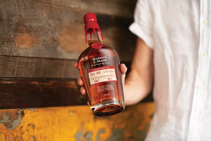 Person in white shirt holding Maker's Mark Limited Release bourbon whisky
