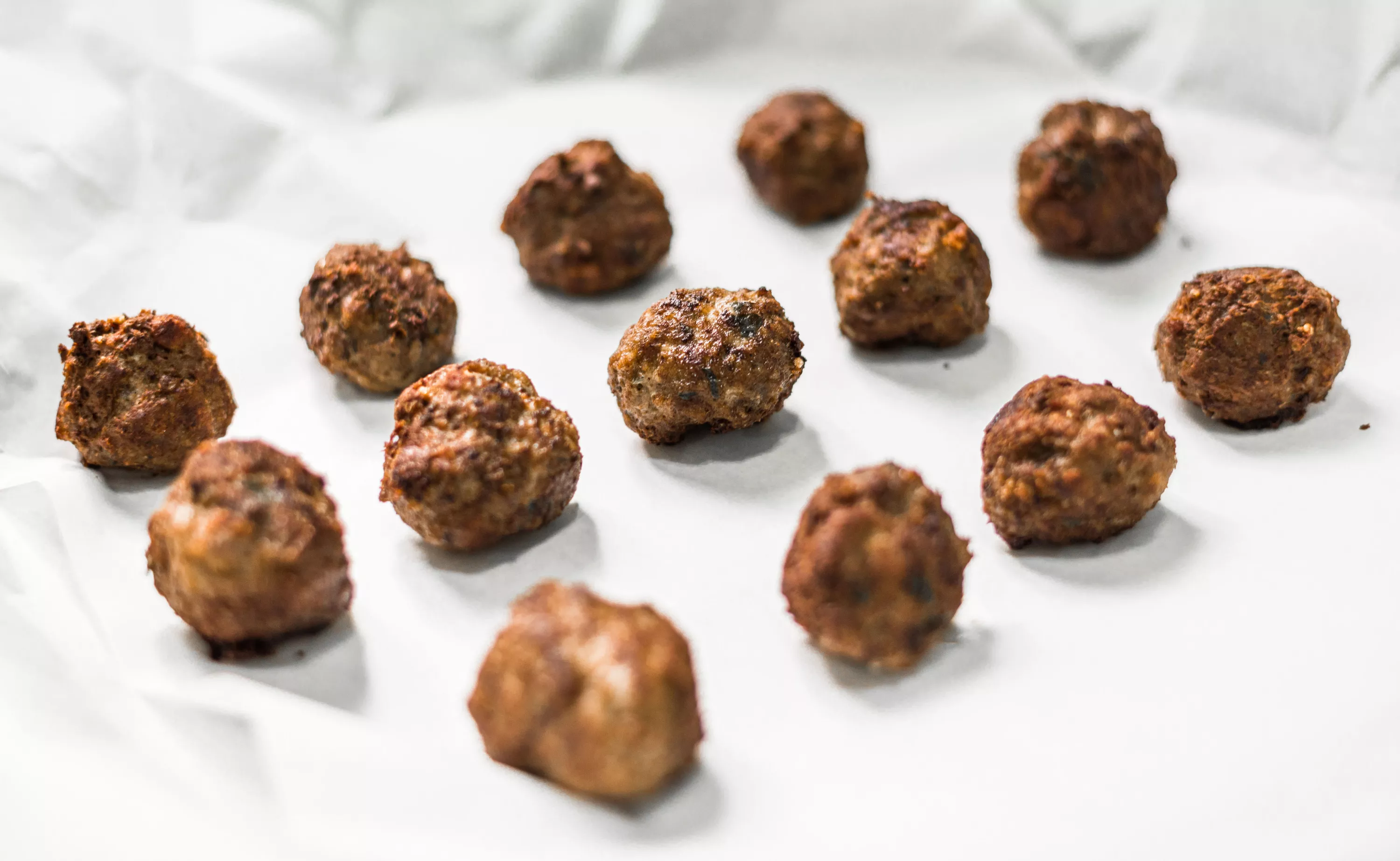 Cooked meatballs are lined up on a serving platter.