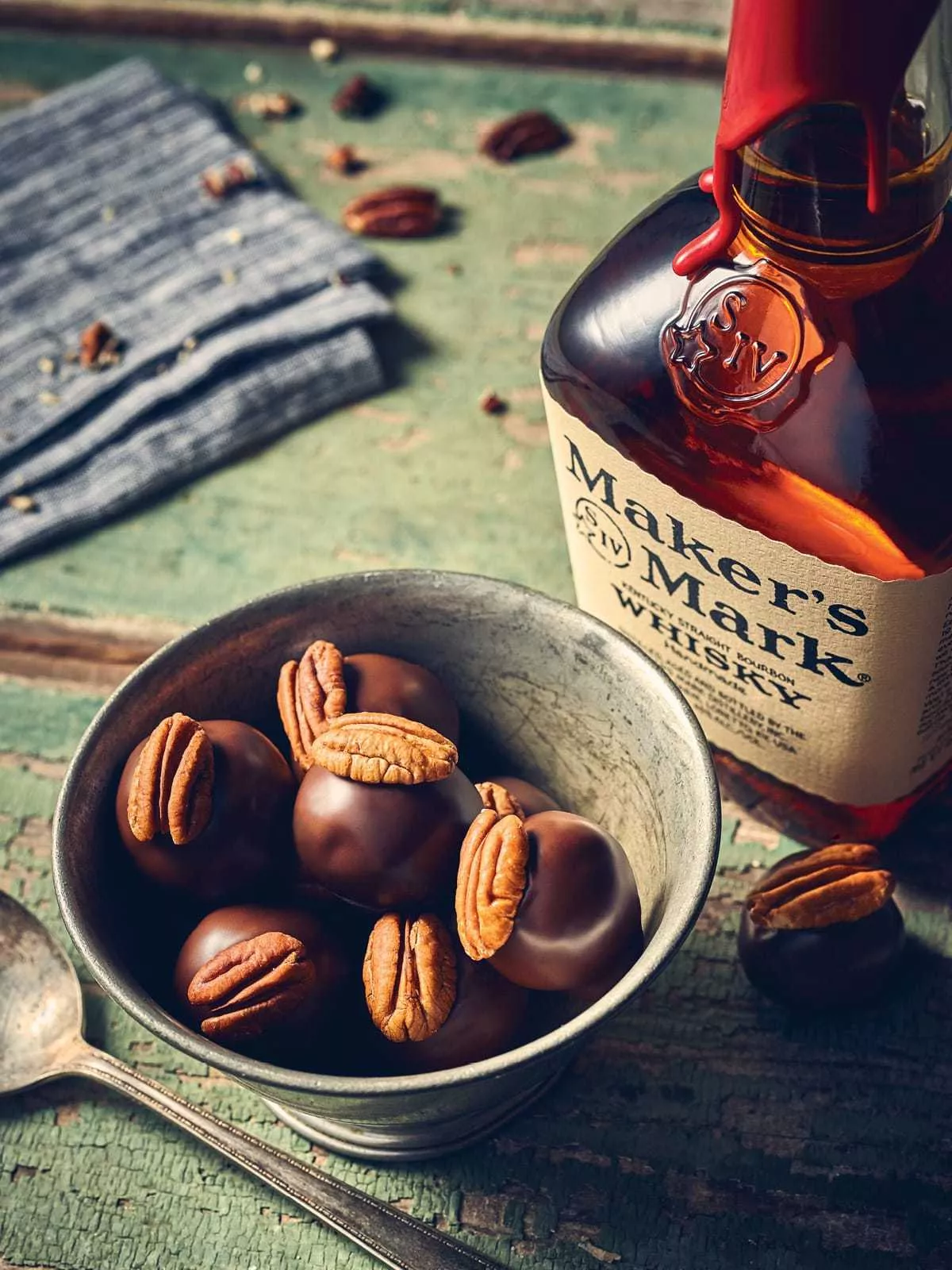 A bottle of Maker's Mark Classic sits next to a bowl of chocolate and pecan bourbon balls.