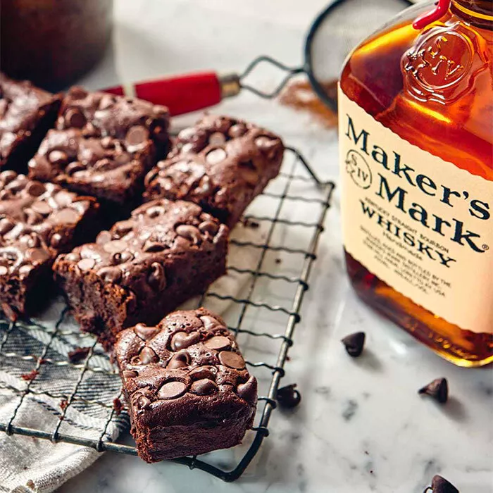 flourless brownies sitting on oven cooking tray next to bottle of makers mark bourbon on a table