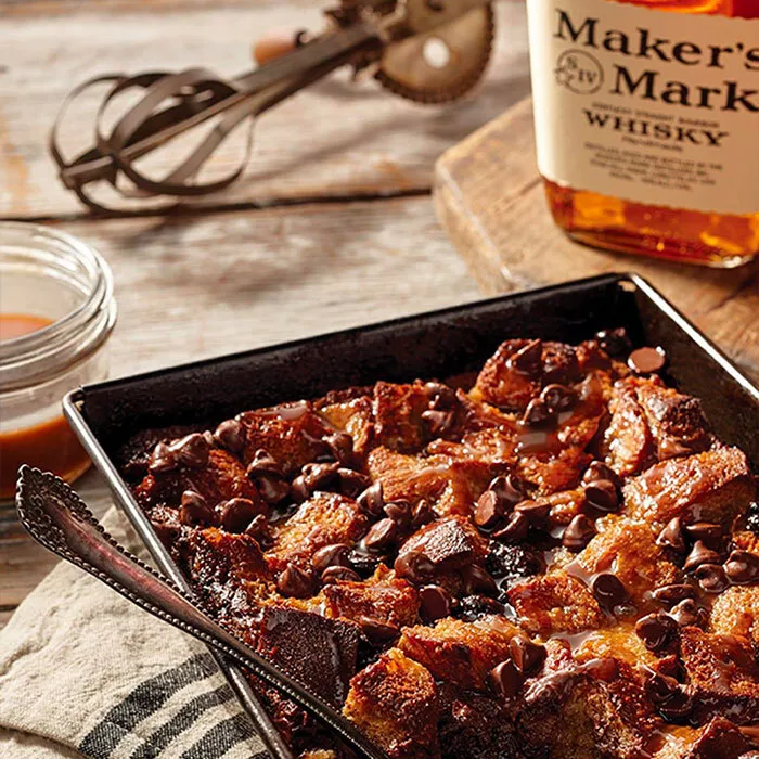 star hill provision bread pudding in baking pan next to sauce and makers mark bottle on table